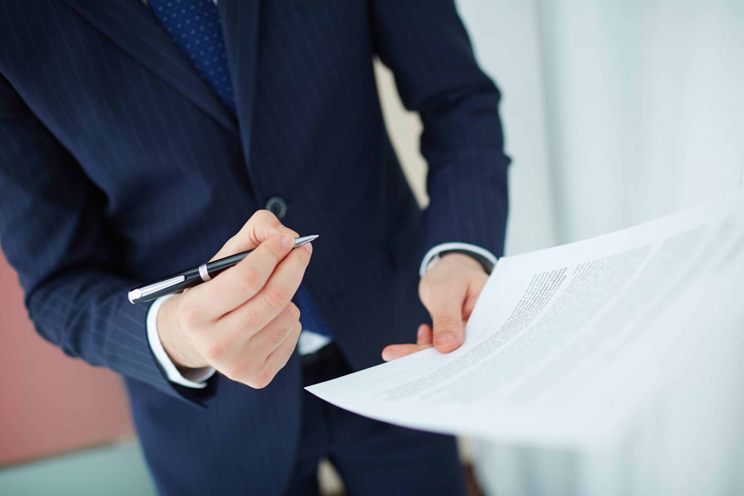 Image of human hand with pen and contract